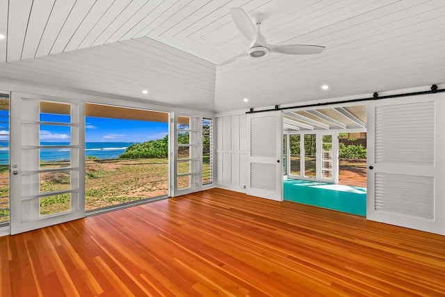 unfurnished sunroom with wooden ceiling, a water view, vaulted ceiling, ceiling fan, and a barn door