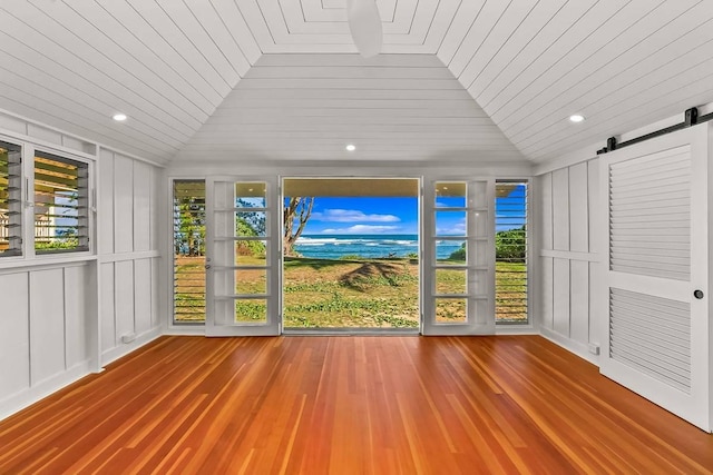 unfurnished sunroom with a barn door, a healthy amount of sunlight, wood ceiling, and lofted ceiling