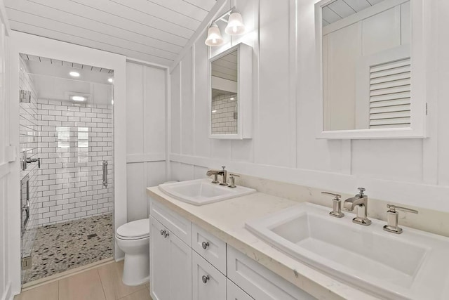 bathroom featuring toilet, vanity, tile patterned floors, and a shower with door