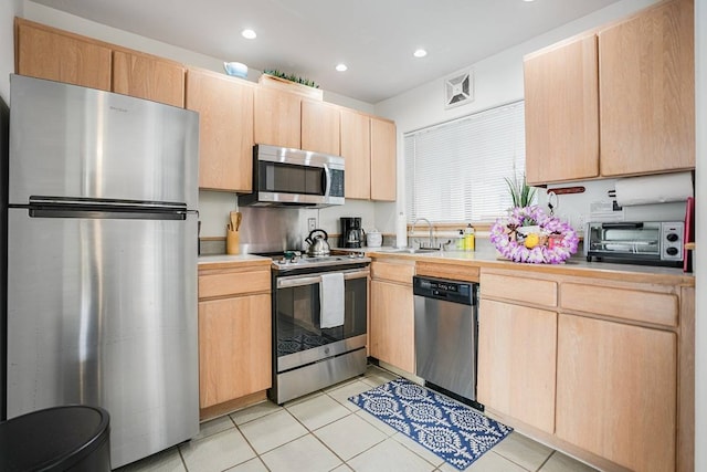 kitchen with light brown cabinetry, stainless steel appliances, light tile floors, and sink