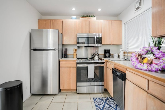 kitchen with light brown cabinetry, stainless steel appliances, sink, and light tile floors