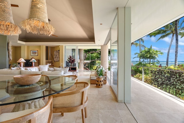 tiled dining space featuring a raised ceiling, a towering ceiling, and a water view