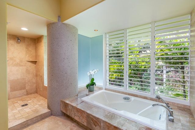 bathroom featuring tile patterned flooring, plenty of natural light, and a relaxing tiled tub