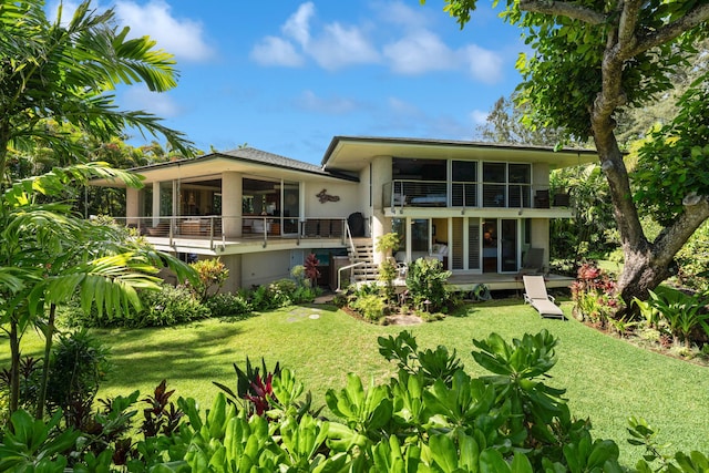 rear view of property featuring a balcony and a yard