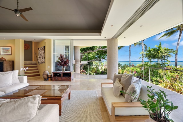 living room with ceiling fan, a raised ceiling, and a water view