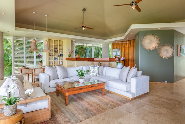 tiled living room with ceiling fan, a wealth of natural light, and a tray ceiling