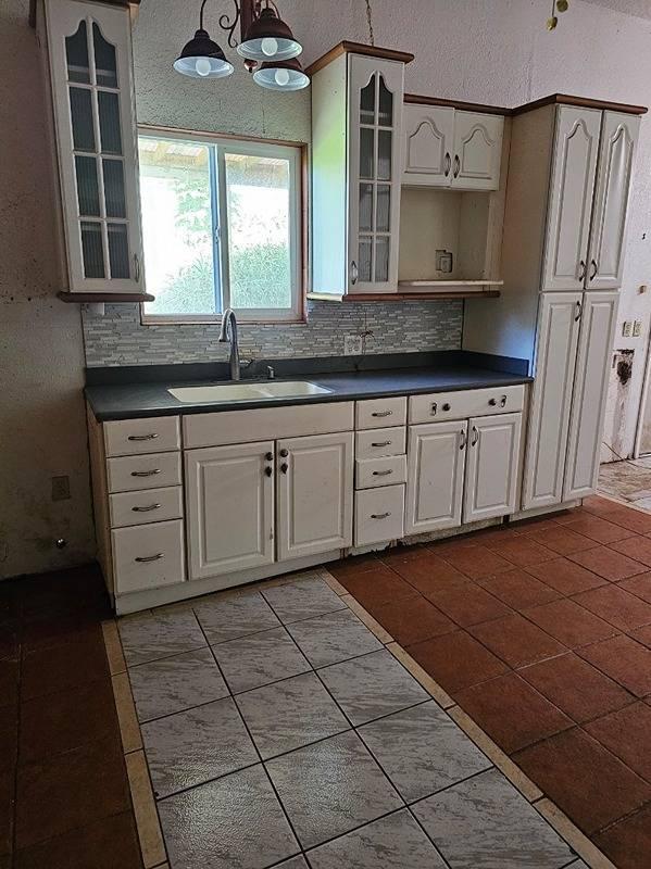 kitchen with white cabinets, light tile patterned flooring, hanging light fixtures, and sink