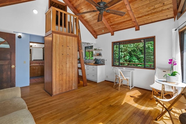 living room with beam ceiling, light wood-type flooring, high vaulted ceiling, ceiling fan, and wooden ceiling