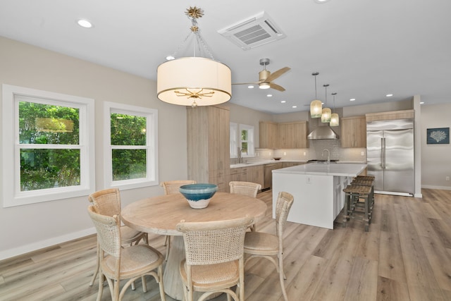 dining room with ceiling fan, light wood-type flooring, and sink