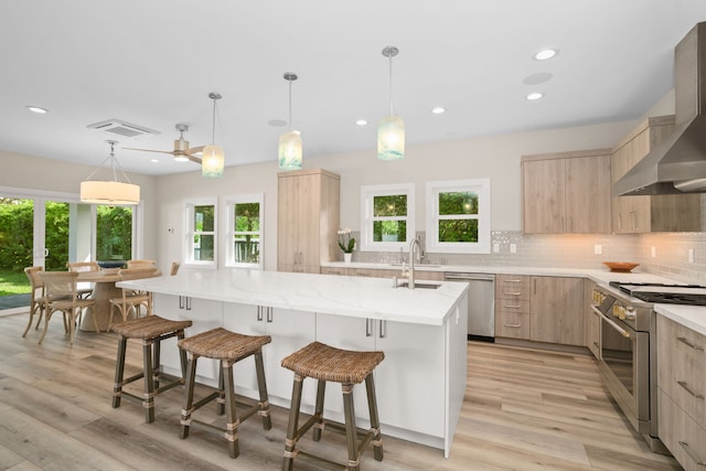 kitchen featuring light brown cabinets, backsplash, stainless steel appliances, and wall chimney exhaust hood