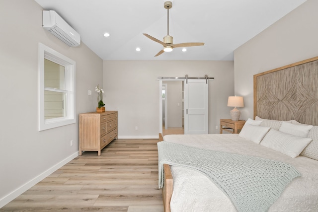 bedroom featuring a wall unit AC, ceiling fan, a barn door, light hardwood / wood-style flooring, and lofted ceiling