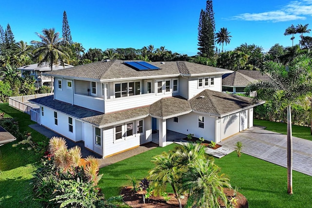 back of property featuring a yard, a garage, and solar panels