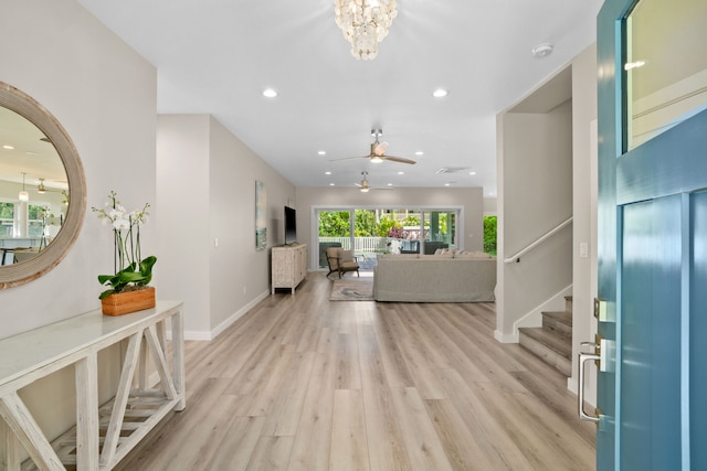 entrance foyer with ceiling fan with notable chandelier and light hardwood / wood-style flooring