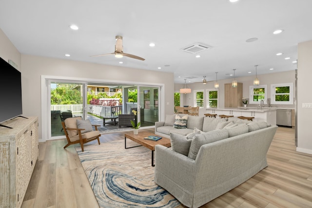 living room featuring a wealth of natural light, ceiling fan, and light wood-type flooring