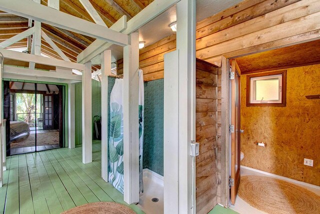 bathroom featuring wood-type flooring and vaulted ceiling with beams