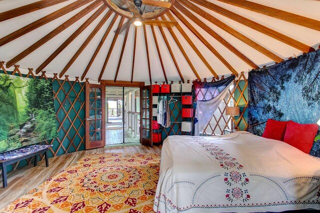 bedroom featuring access to outside, lofted ceiling, and light wood-type flooring