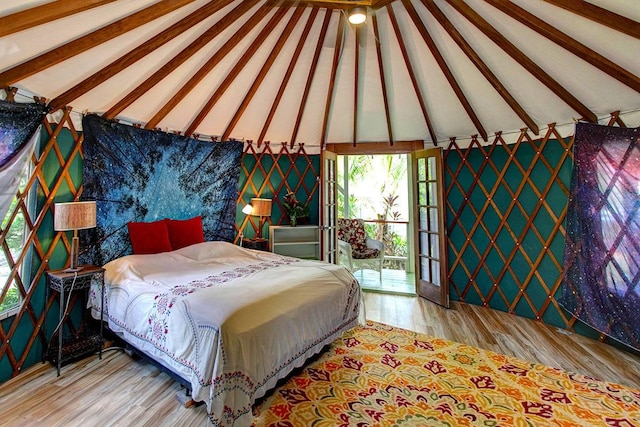 bedroom featuring access to outside, vaulted ceiling with beams, and light hardwood / wood-style floors