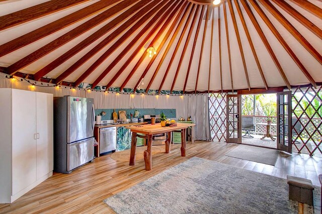 kitchen featuring light wood-type flooring, stainless steel appliances, high vaulted ceiling, and sink