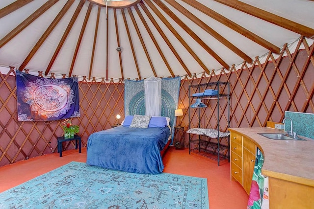 bedroom featuring light carpet, vaulted ceiling with beams, and sink