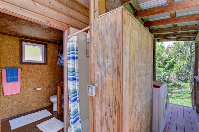 bathroom with washer / clothes dryer, beamed ceiling, wood-type flooring, and toilet