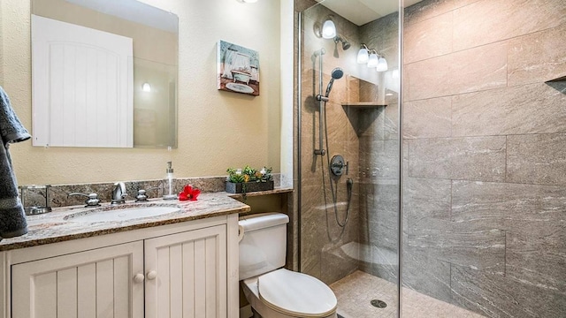 bathroom with tiled shower, vanity, and toilet