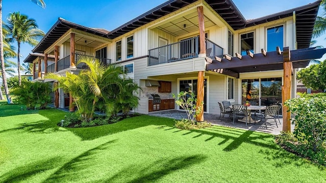 rear view of house with a yard, an outdoor kitchen, a balcony, and a patio area