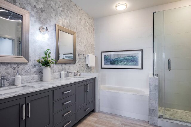 bathroom with shower with separate bathtub, vanity with extensive cabinet space, double sink, and wood-type flooring