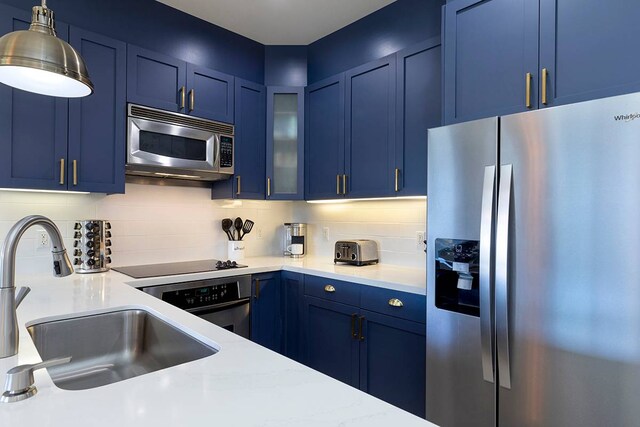 kitchen with backsplash, decorative light fixtures, appliances with stainless steel finishes, and sink