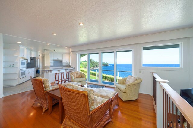 living room featuring a water view, light hardwood / wood-style flooring, and a textured ceiling