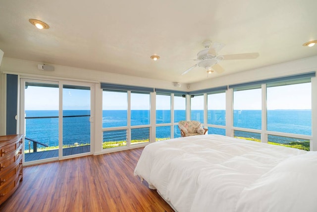 bedroom with a water view, dark hardwood / wood-style floors, and access to exterior