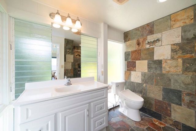 bathroom with toilet, tile flooring, oversized vanity, and tile walls