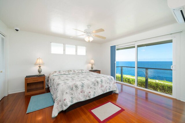 bedroom with a closet, ceiling fan, dark wood-type flooring, and a water view