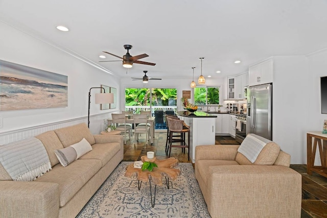 living room with ceiling fan, ornamental molding, and sink