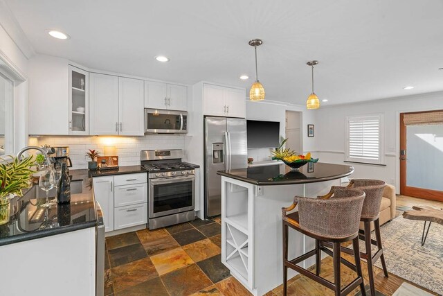 kitchen with stainless steel appliances, backsplash, and white cabinetry