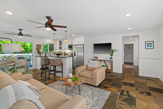 tiled living room with ceiling fan and ornamental molding