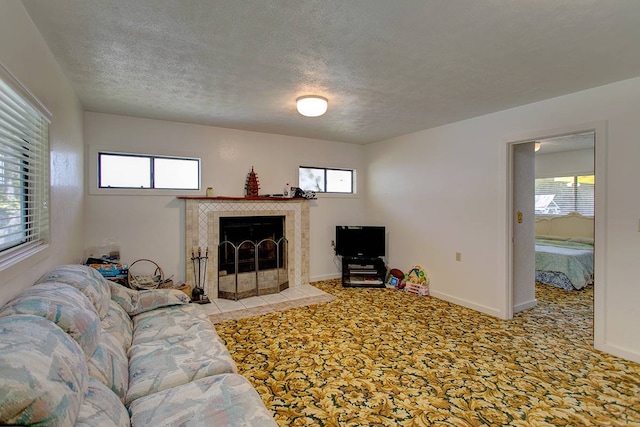 living room with a textured ceiling, a healthy amount of sunlight, and a tiled fireplace