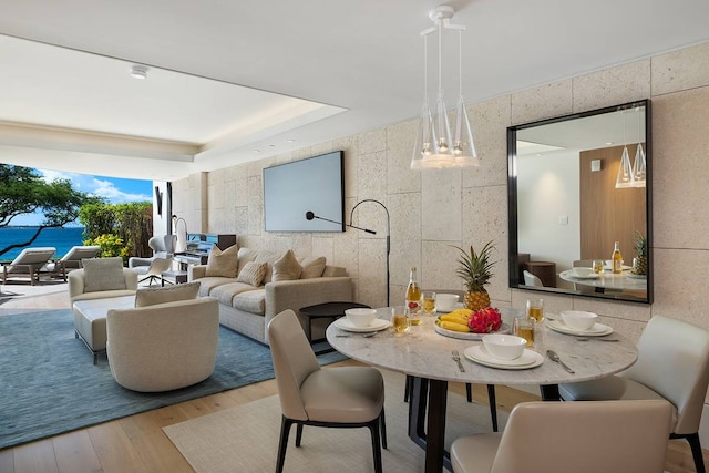 dining area with tile walls, a tray ceiling, and wood-type flooring