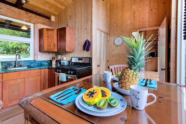 kitchen featuring wood ceiling, gas range, wooden walls, sink, and light hardwood / wood-style floors