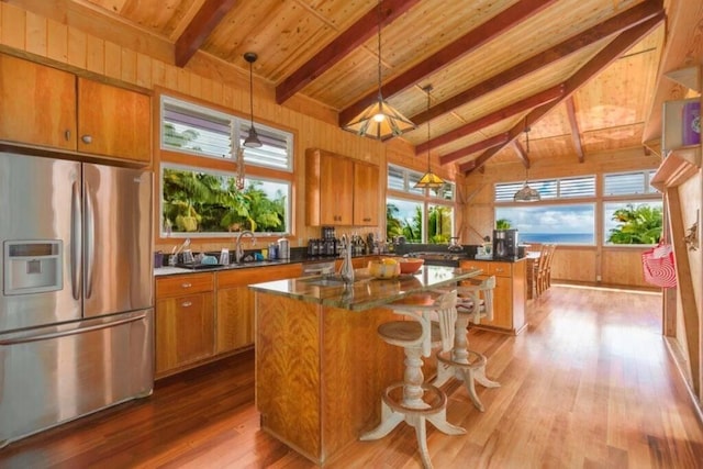 kitchen featuring stainless steel refrigerator with ice dispenser, hardwood / wood-style flooring, decorative light fixtures, wooden ceiling, and a center island