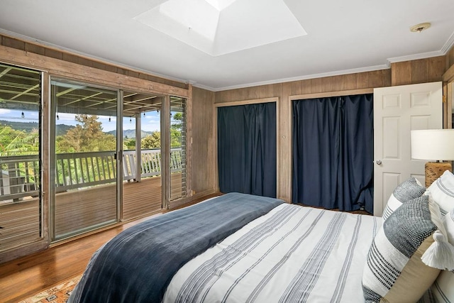 bedroom featuring ornamental molding, a skylight, access to outside, wood-type flooring, and wood walls