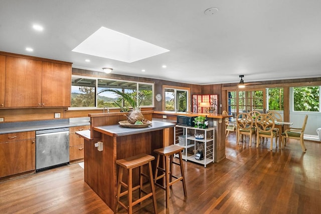 kitchen featuring a center island, stainless steel dishwasher, dark wood-type flooring, and a healthy amount of sunlight