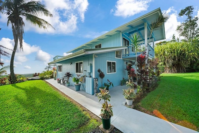 rear view of property with a yard and a balcony