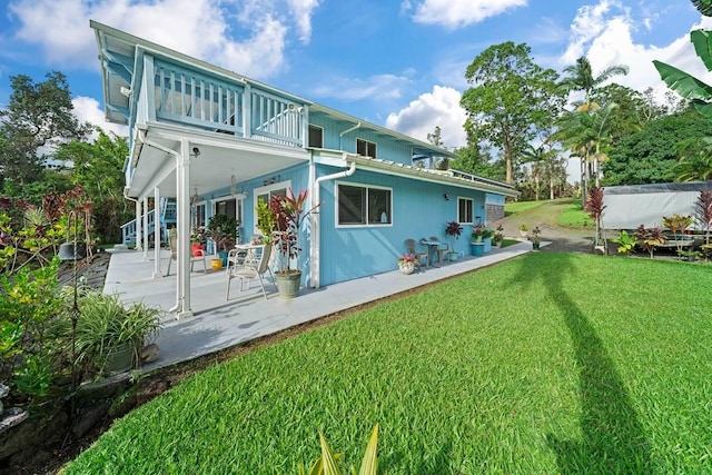 back of property featuring a lawn, a patio area, and a balcony