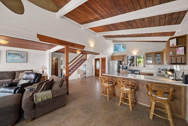 kitchen with beam ceiling, tasteful backsplash, kitchen peninsula, a breakfast bar area, and appliances with stainless steel finishes