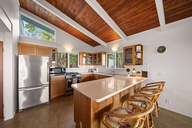 kitchen with wooden ceiling, decorative backsplash, appliances with stainless steel finishes, kitchen peninsula, and a breakfast bar area