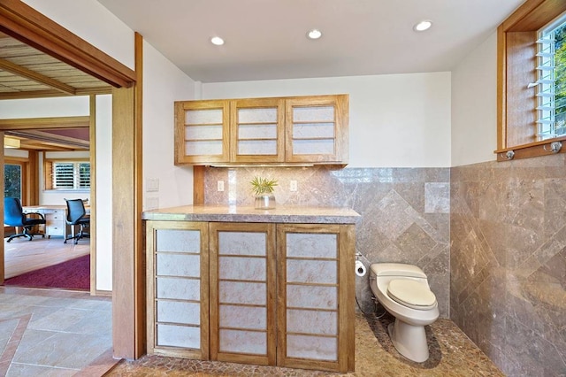 bathroom with tasteful backsplash, toilet, vanity, tile walls, and tile floors