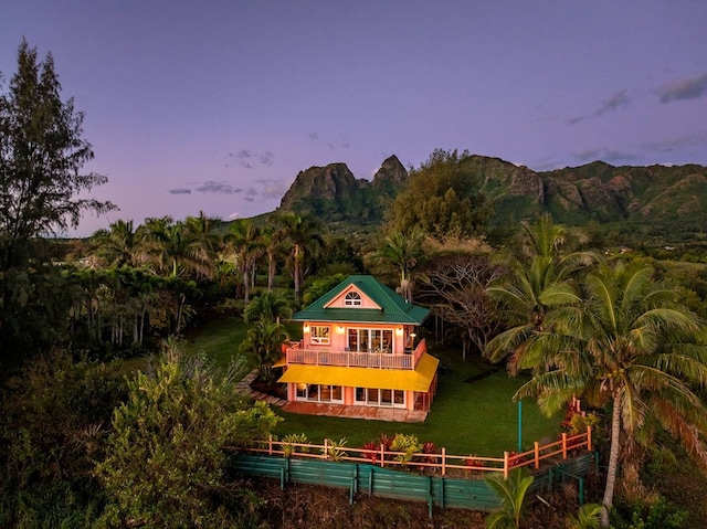 back house at dusk featuring a mountain view and a yard