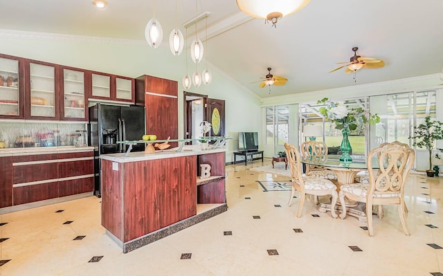 kitchen featuring ceiling fan, a kitchen island with sink, high vaulted ceiling, decorative light fixtures, and black refrigerator with ice dispenser