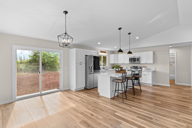 kitchen with a kitchen island, appliances with stainless steel finishes, white cabinetry, hanging light fixtures, and light wood-type flooring