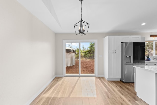 unfurnished dining area with an inviting chandelier and light hardwood / wood-style flooring